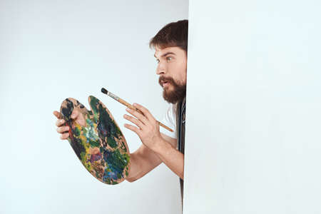 Male artist hiding behind an easel palette drawing art