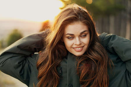 Pretty woman in a dark jacket straightens her hair close-up nature