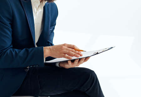 Business man in a suit with documents writes down important informationの写真素材