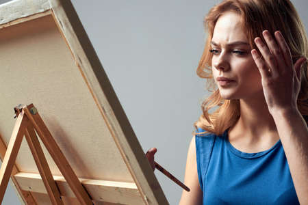 Woman artist with brush paint on easel art hobby light backgroundの写真素材
