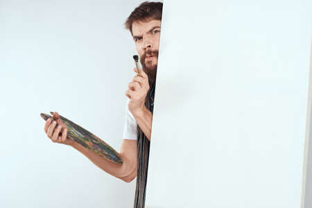 Male artist hiding behind an easel palette drawing artの写真素材