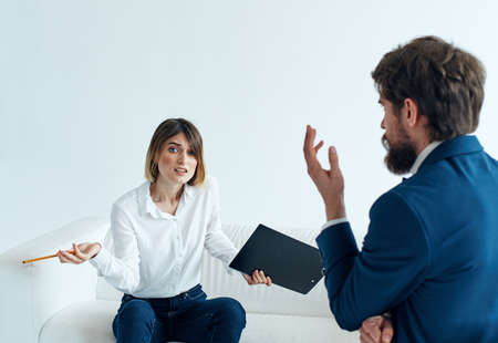 Business man in a classic suit and a woman on the couch with documents in the hands of a...
