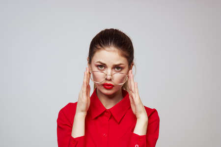 fashionable woman in a red shirt on a light background fun emotions bright makeup glasses attractive appearanceの写真素材