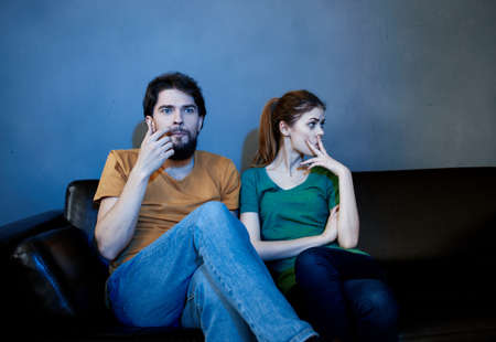 Offended woman on the couch in the evening watching TV and a manの写真素材