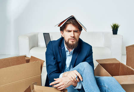 Business man with boxes sits on the office floor unpacking thingsの写真素材