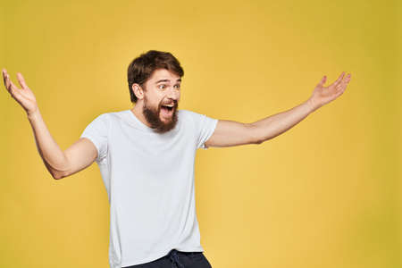 Man gesturing with hands emotions lifestyle white t-shirt yellow isolated background