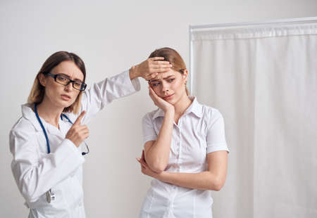 Doctor woman measures the temperature of the patient and a stethoscope on the neck