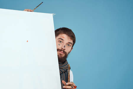 Male artist backs up behind easel brush art creativity blue backgroundの写真素材