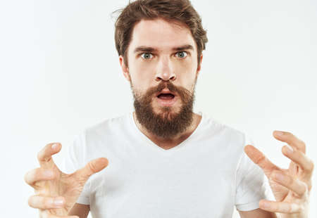 Energetic man in white t-shirt bushy beard gestures with hands cropped view