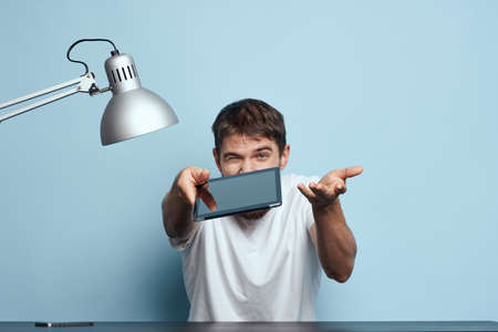Man with tablet at table indoors and lamp work office freelancer blue background
