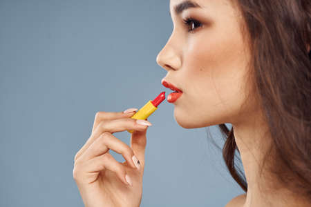 Woman with lipstick on a gray background brunette makeup with eye shadow on the eyelids