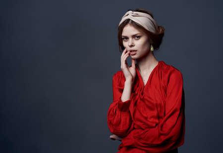 Attractive woman in red dress decorating turban on her head studio cropped view