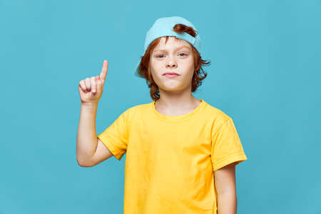 redhead boy in blue cap cropped points finger up
