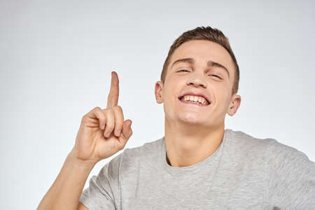 Cheerful emotional man gray t-shirt gesturing with hands studio lifestyleの写真素材