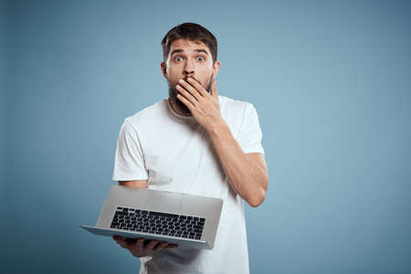 Emotional man with laptop in hands on blue background monitor keyboard internet model cropped view