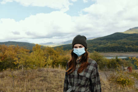 Portrait of a woman in the mountains with a medical mask on her face