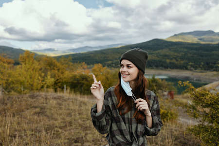 A woman with a medical mask is gesturing with her hands outdoors in the forestの写真素材