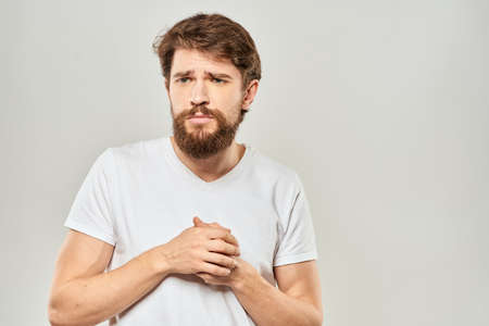 man in white t-shirt gesturing with his hands studio dissatisfaction lifestyle light background
