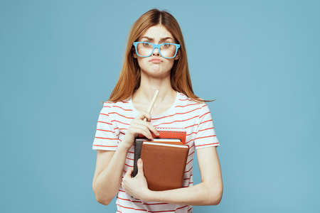 girl in fashionable glasses with notebooks in hands on a blue background cropped