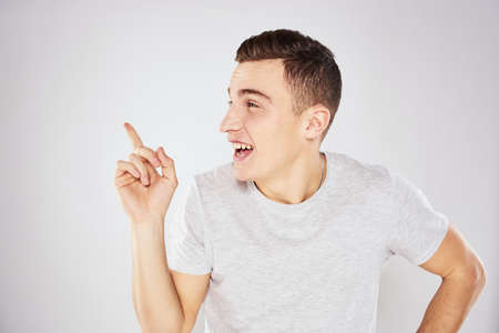 Man in a white t-shirt emotions gestures with hands close-up cropped view light background