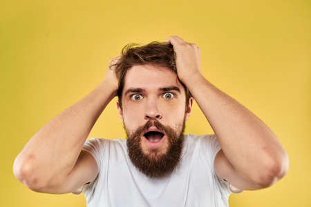 A man in a white t-shirt gestures with his hands lifestyle cropped view yellow background more funの写真素材