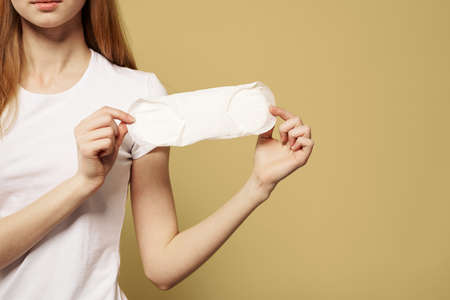 Girl with a clean pad in her hand on a beige background cropped view of menstruation critical days...
