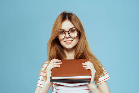 energetic female student with notepads and glasses model blue backgroundの写真素材