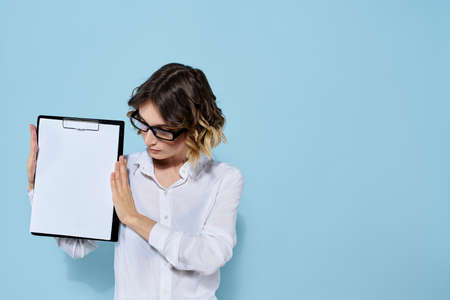 Business woman with documents in a folder on a blue background and in a light shirt glasses on her faceの写真素材