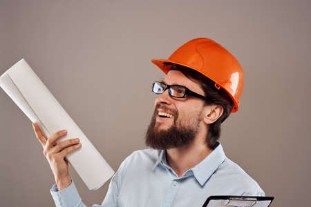 Male engineer with glasses in orange paint. Professional blueprints in hands