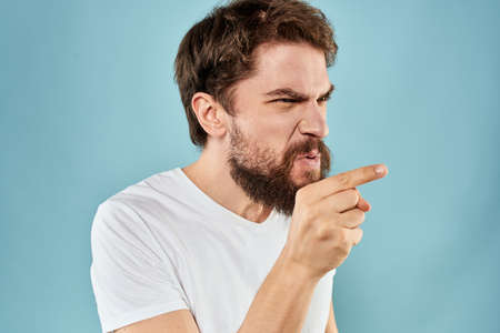 Man with disgruntled facial expression gesturing with hands studio lifestyle blue background