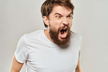 man in white t-shirt emotions expressions gesture with hands cropped view light backgroundの写真素材