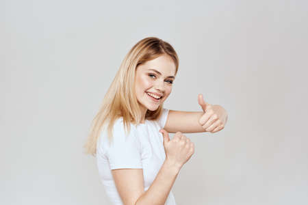 Cute blonde white t-shirt gesture with hands lifestyle light backgroundの写真素材