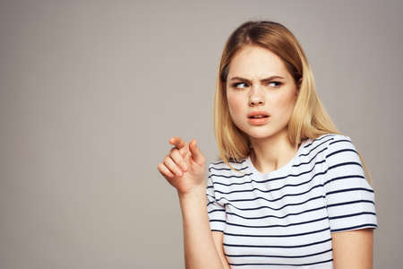 A woman with a displeased expression is gesturing with her hands T-shirt gray backgroundの写真素材