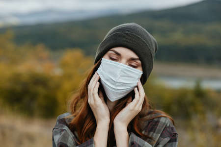 Portrait of a woman in the mountains with a medical mask on her face and closed eyesの写真素材
