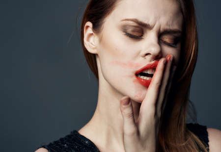 Charming woman smears lipstick all over her face