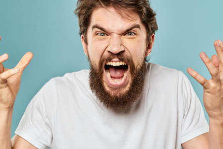 Bearded man emotions facial expression gestures hands close-up blue backgroundの写真素材