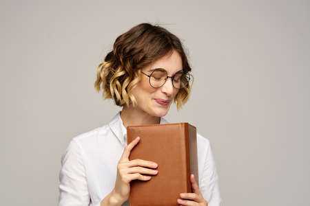 woman with notepad in hands business work beige background glasses hairstyle