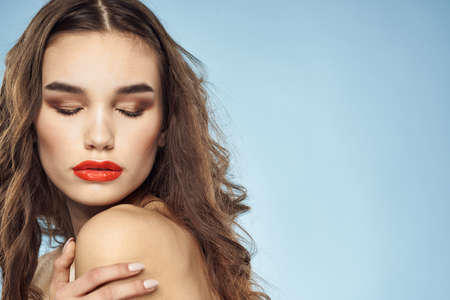 Elegant brunette fashionable hairstyle bright makeup naked shoulders close-up blue backgroundの写真素材