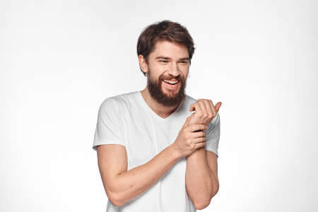 Bearded man in white t-shirt gesture with hands emotions light background