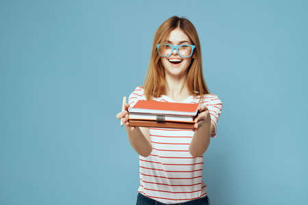girl in fashionable glasses with notebooks in hands on a blue background cropped view Copy Space