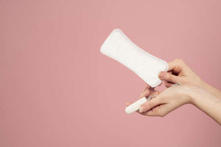 Protective pad and tampon in female hands on a pink background menstruation critical daysの写真素材
