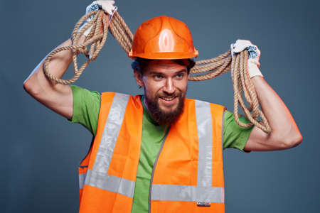 A bearded man construction worker in an orange hard hat safety rope in his handsの写真素材