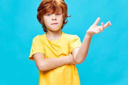 Red-haired boy gesturing with hand emotion yellow t-shirt cropped viewの写真素材