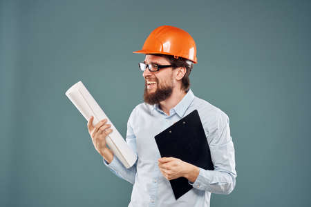 A male engineer in an orange hard hat with documents in the hands of construction drawings