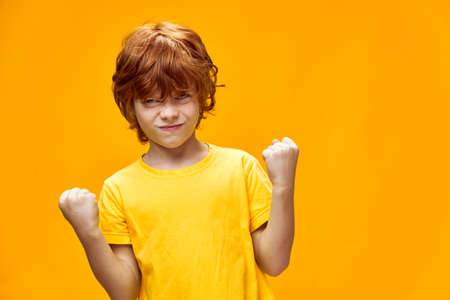 red-haired boy holding hands in fists on isolated backgroundの写真素材