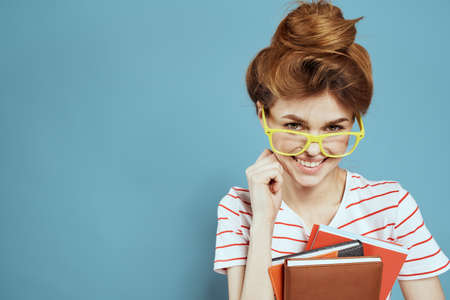 energetic female student with notepads and glasses model blue background