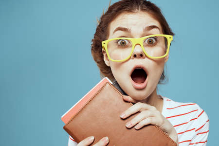 Beautiful female student with notepads and in yellow glasses on a blue background education science...