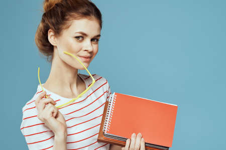 Beautiful female student with notepads and in yellow glasses on a blue background education science instituteの写真素材