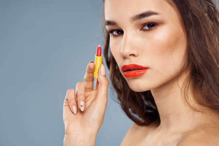 Woman with lipstick on a gray background brunette makeup with eye shadow on the eyelidsの写真素材