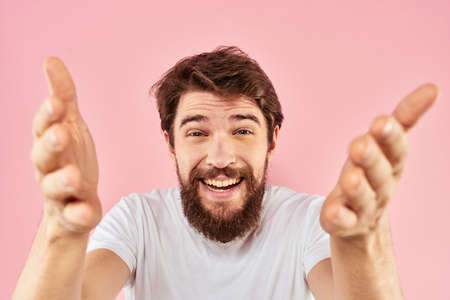 Bearded man in white t-shirt gesturing with hands facial expression close up pink backgroundの写真素材